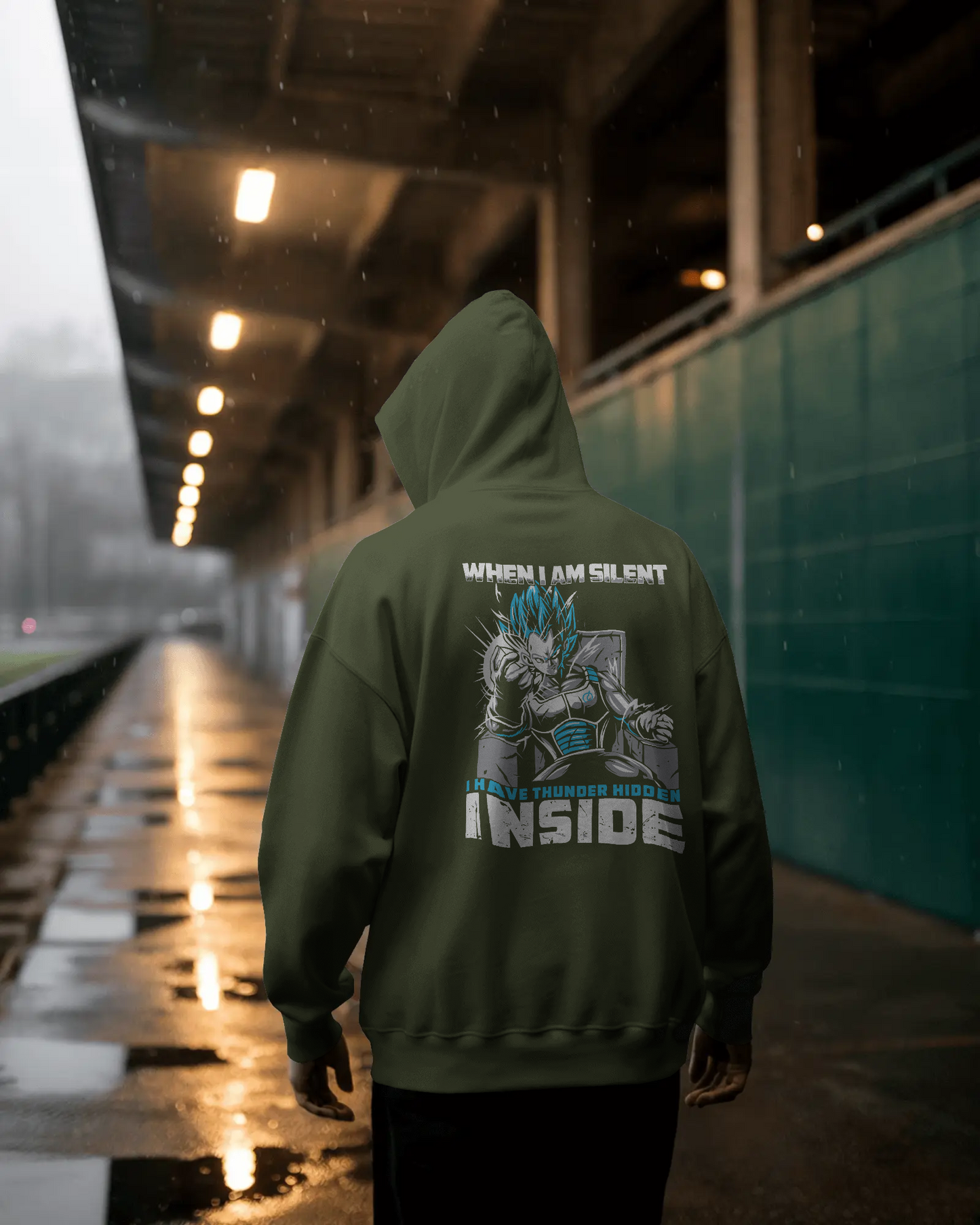 Person wearing a green hoodie with a graphic design and text on the back, standing in a wet, urban setting.