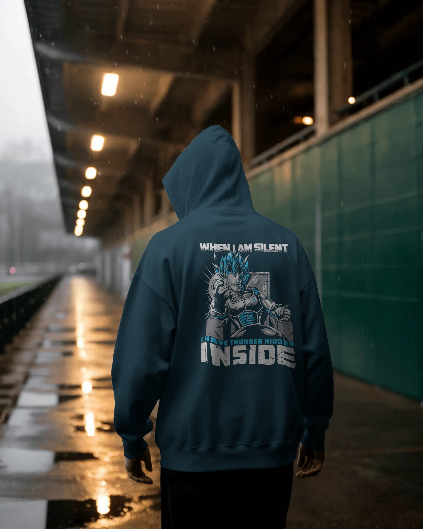 Person wearing a hoodie with a graphic design and text in a dimly lit urban setting.